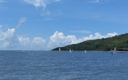 孩子們在沙灘玩沙,大人們坐在傘下暢談,海里有揚起的帆船,馳騁的遊艇